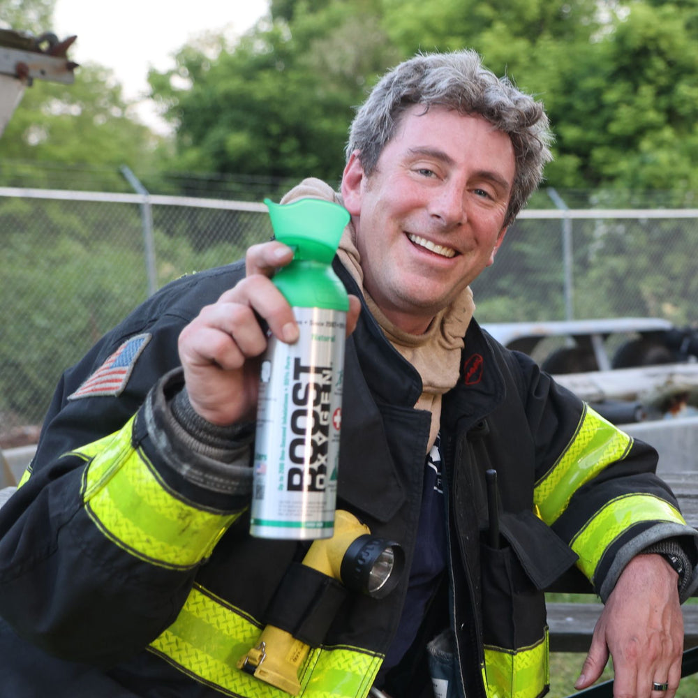 Male Fire fighter smiling holding a can of Boost Oxygen.