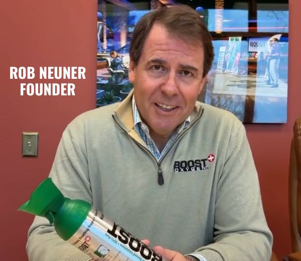 Rob Neuner, Founder, holds a Boost Health can in an indoor office setting with a red wall and picture behind him.
