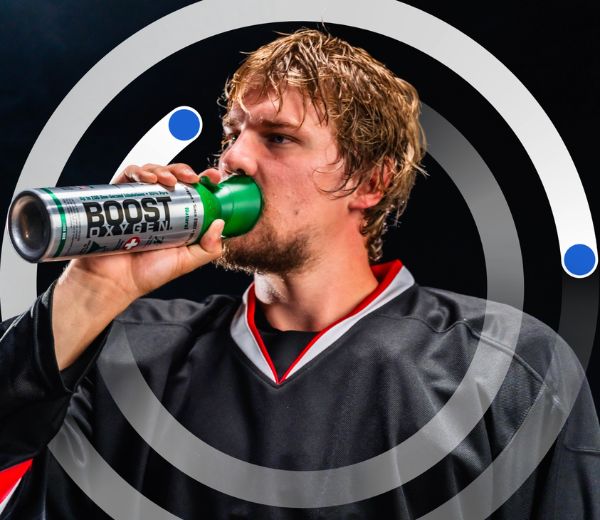A man in a hockey jersey using a Boost Oxygen can, set against a dark background with a circular graphic over him.