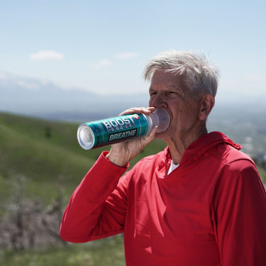 Older man in the mountains using Boost Oxygen Breathe.