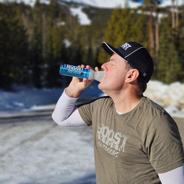Man using Boost Oxygen Revive can in the mountains with snow in the background.