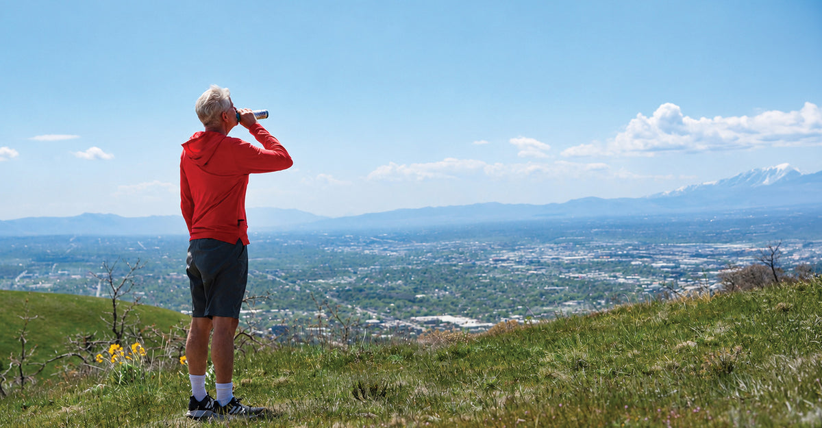Man hiking overlooking a city with the mountains in the background using Boost Oxygen.