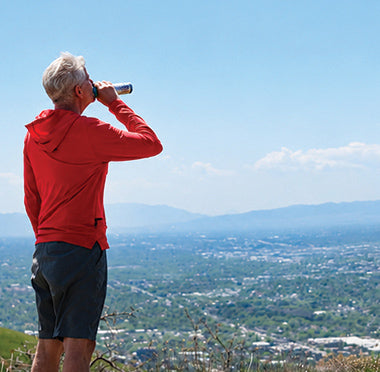 Man hiking overlooking a city with the mountains in the background using Boost Oxygen.