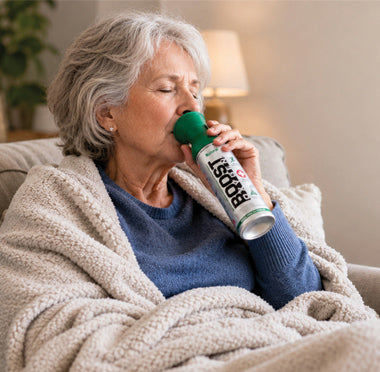 Woman wrapped in a black sitting on a coach using Boost Oxygen.